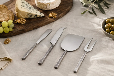 Essential serveware utensils arranged beside a cheese board on a marble countertop in a bright, elegant USA home kitchen setting at home.